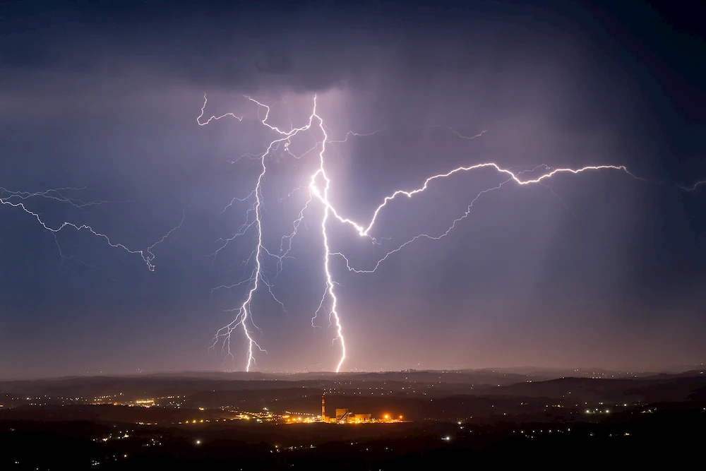 Lightning strike creating ozone during a thunderstorm over city skyline